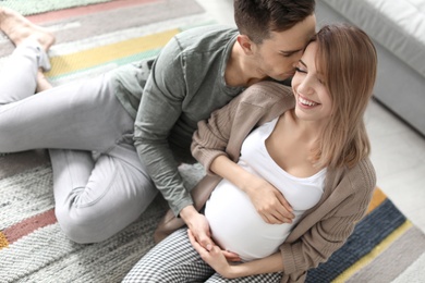 Photo of Young pregnant woman with her husband at home