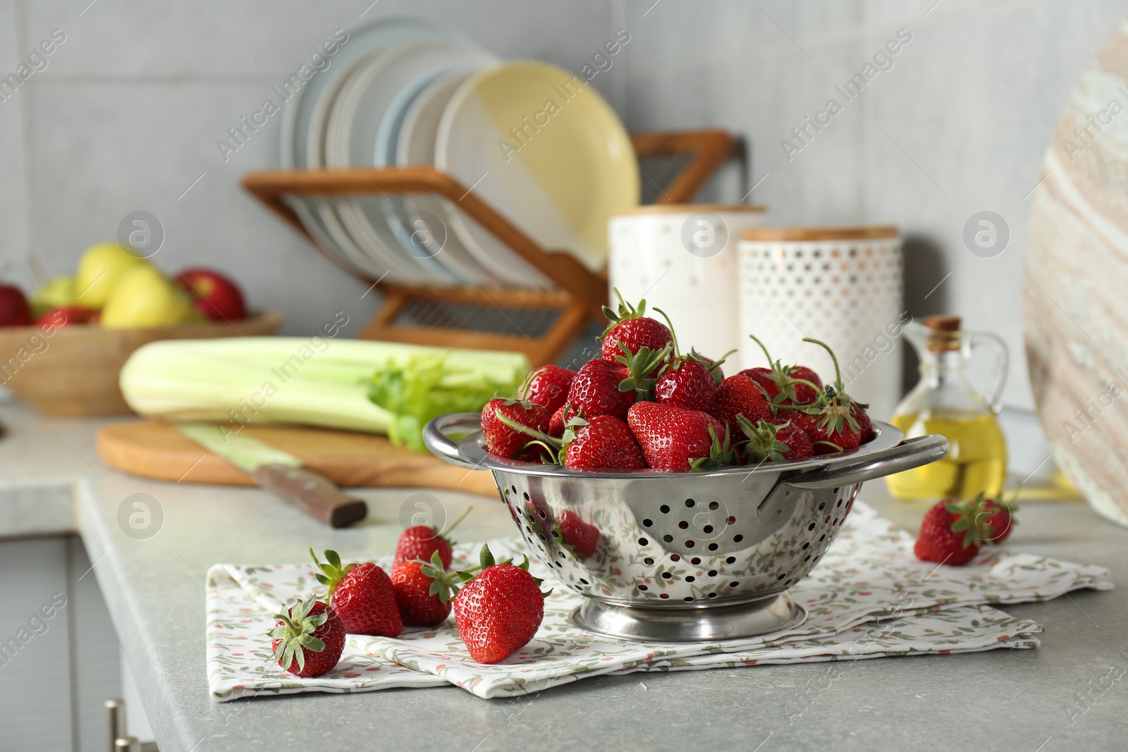 Photo of Metal colander with fresh strawberries on grey countertop in kitchen