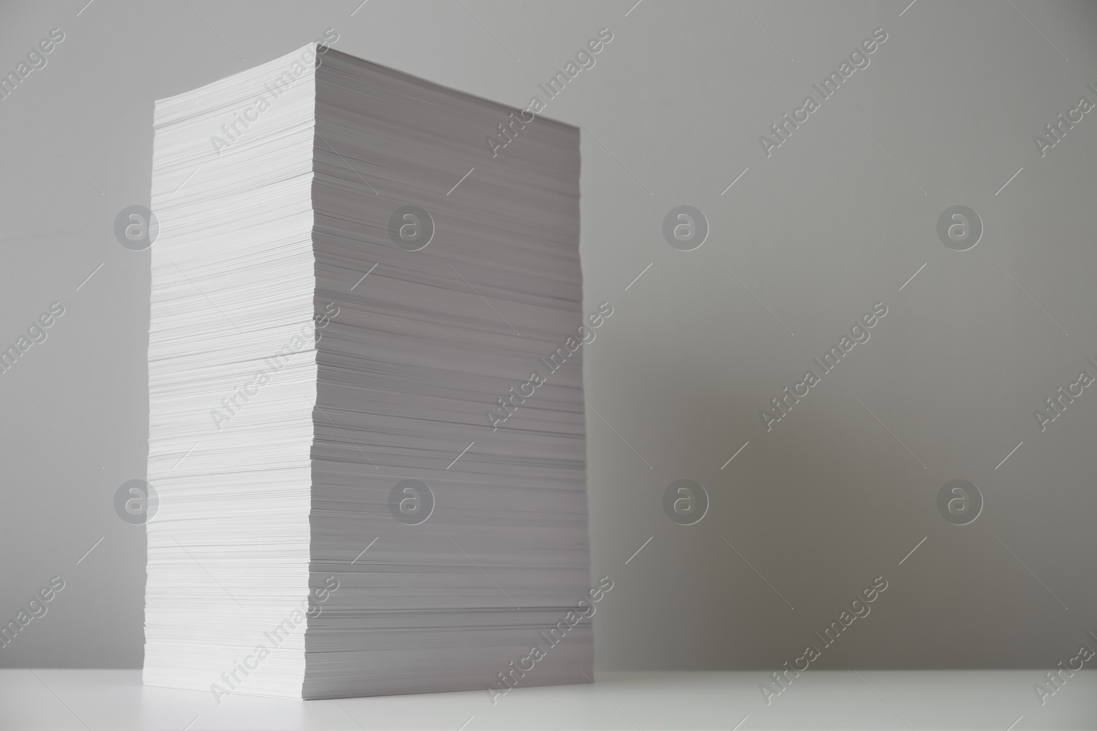 Photo of Stack of paper sheets on white table. Space for text