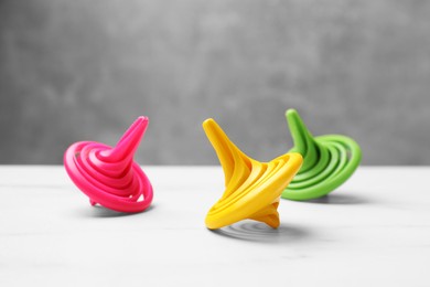 Bright spinning tops on white table, closeup