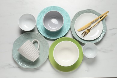 Beautiful ceramic dishware, cup and cutlery on white marble table, flat lay