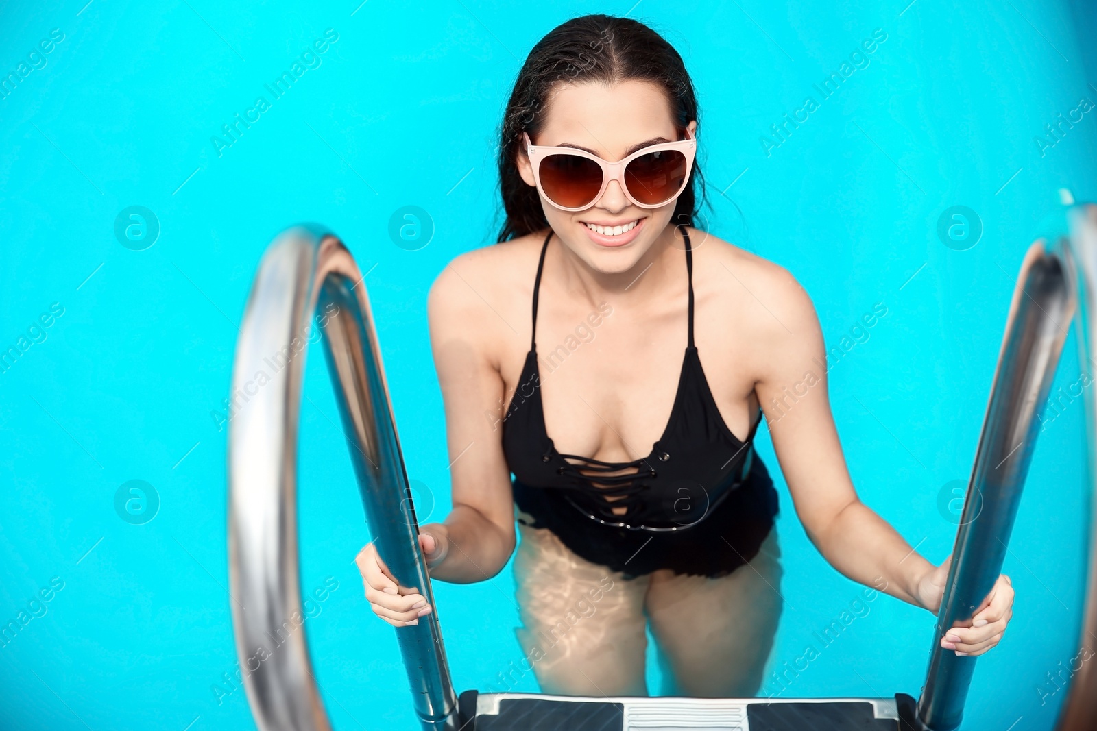 Photo of Beautiful young woman getting out of blue swimming pool