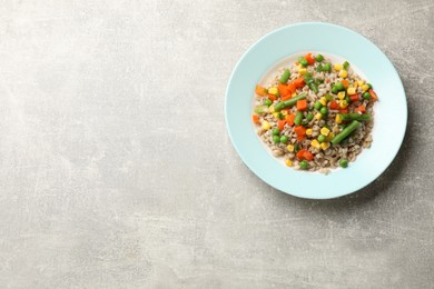 Tasty pearl barley porridge with vegetables on light textured table, top view. Space for text