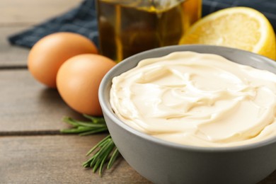 Bowl with fresh mayonnaise and ingredients on wooden table, closeup