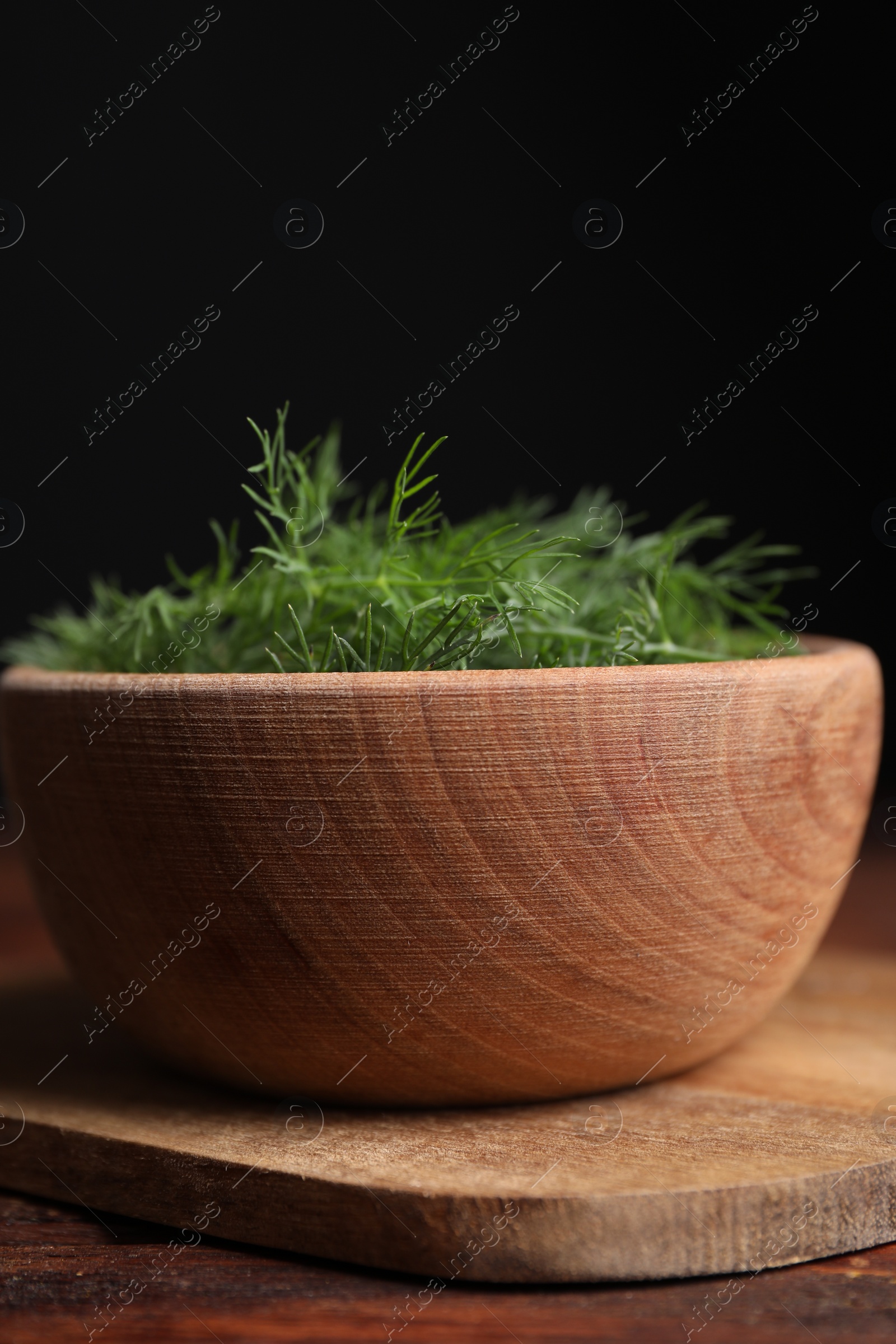 Photo of Bowl of fresh dill on wooden table, closeup