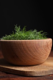 Photo of Bowl of fresh dill on wooden table, closeup