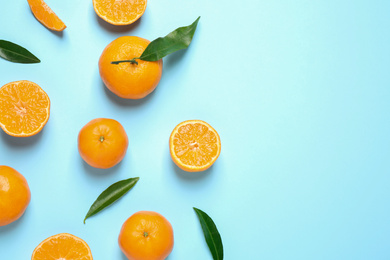 Photo of Flat lay composition with fresh ripe tangerines and leaves on light blue background, space for text. Citrus fruit