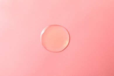 Photo of Drop of hydrophilic oil on pink background, top view