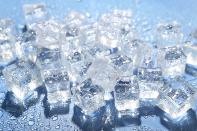 Photo of Melting ice cubes and water drops on blue background, closeup