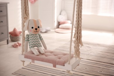 Beautiful swing with toy dog in room. Stylish interior design
