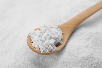 Photo of Heap of natural starch and wooden spoon, closeup