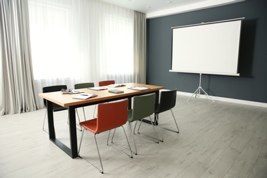 Photo of Modern meeting room interior with large table and projection screen