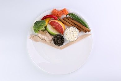 Metabolism. Plate with different food products and wooden cutlery on white background, top view