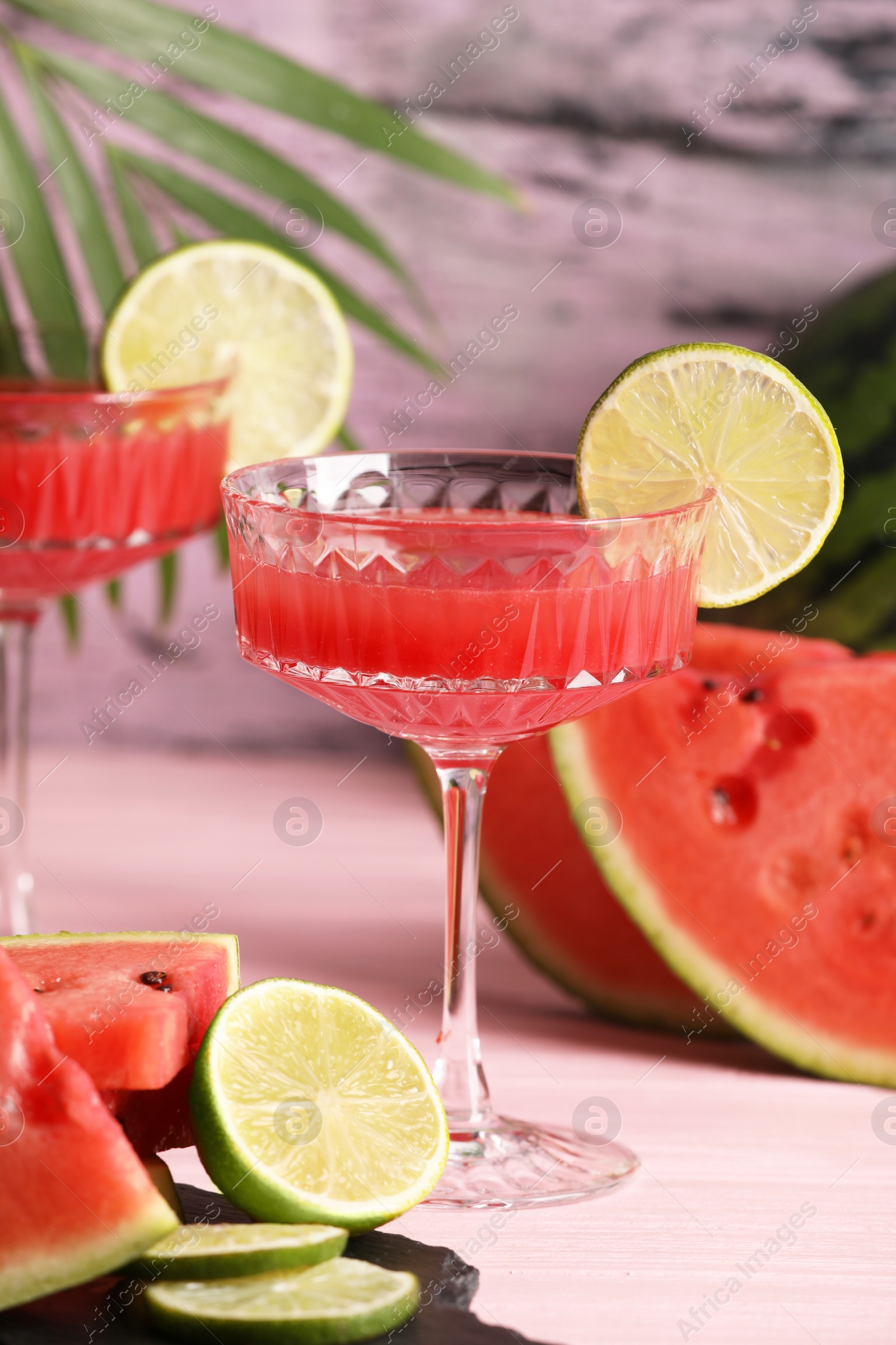 Photo of Cocktail glass of delicious fresh watermelon juice with lime on light wooden table