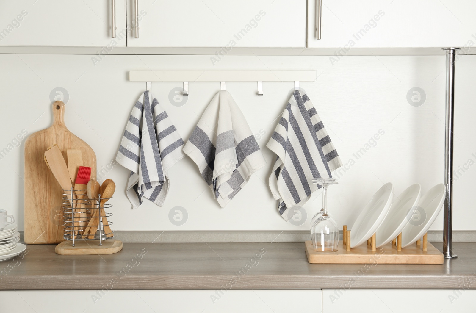 Photo of Different kitchen towels hanging on hook rack indoors