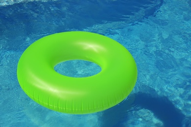 Bright inflatable ring floating in swimming pool on sunny day. Space for text