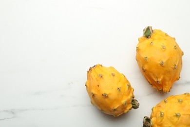 Photo of Delicious yellow pitahaya fruits on white marble table, flat lay. Space for text