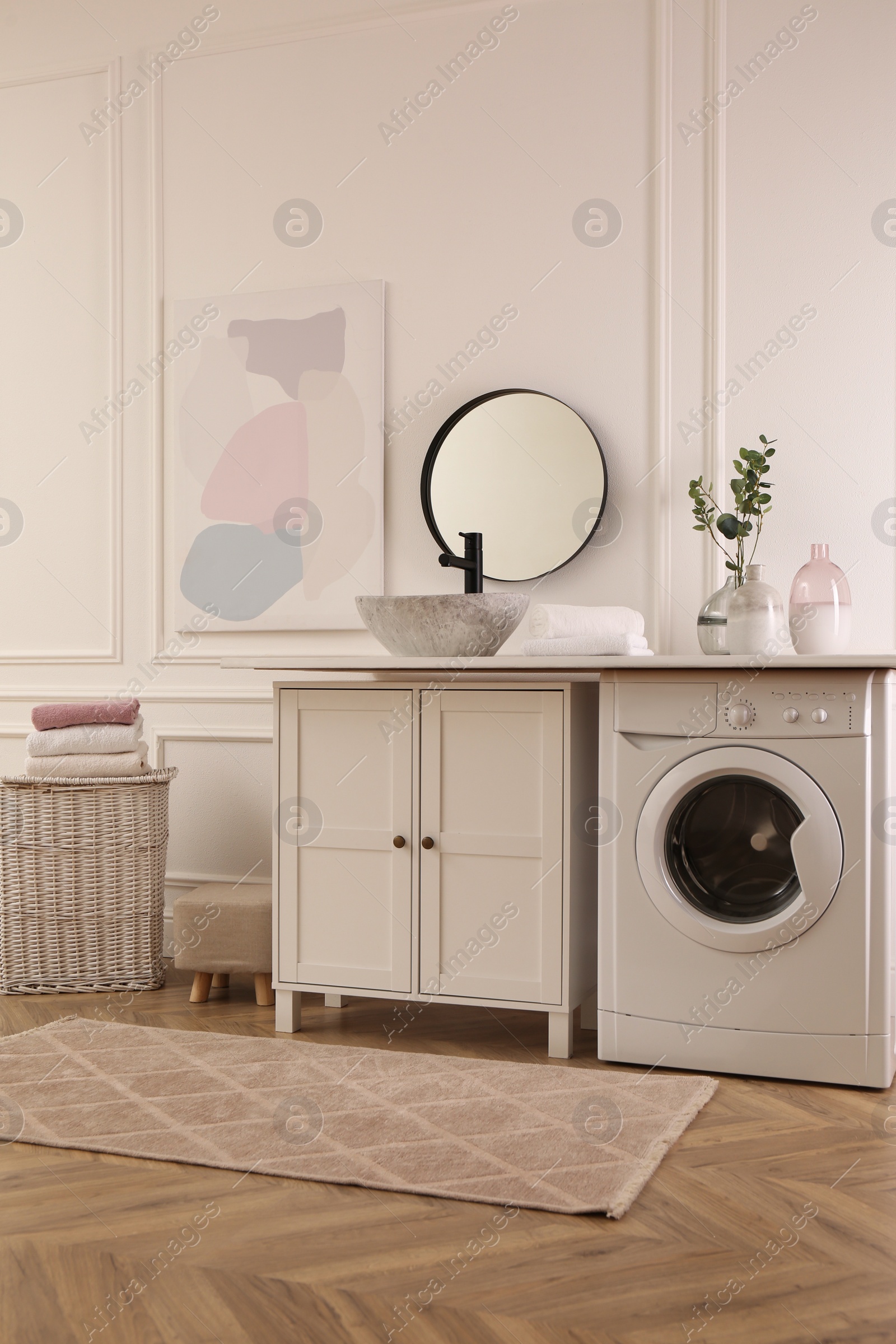 Photo of Laundry room interior with modern washing machine and stylish vessel sink on countertop