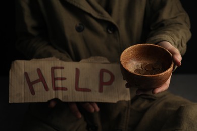 Photo of Poor homeless woman with help sign holding bowl of donations, closeup