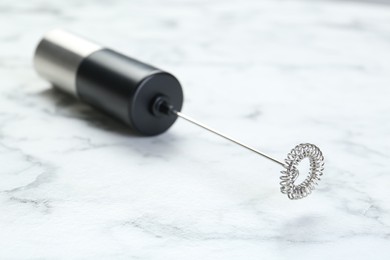 Black milk frother wand on white marble table