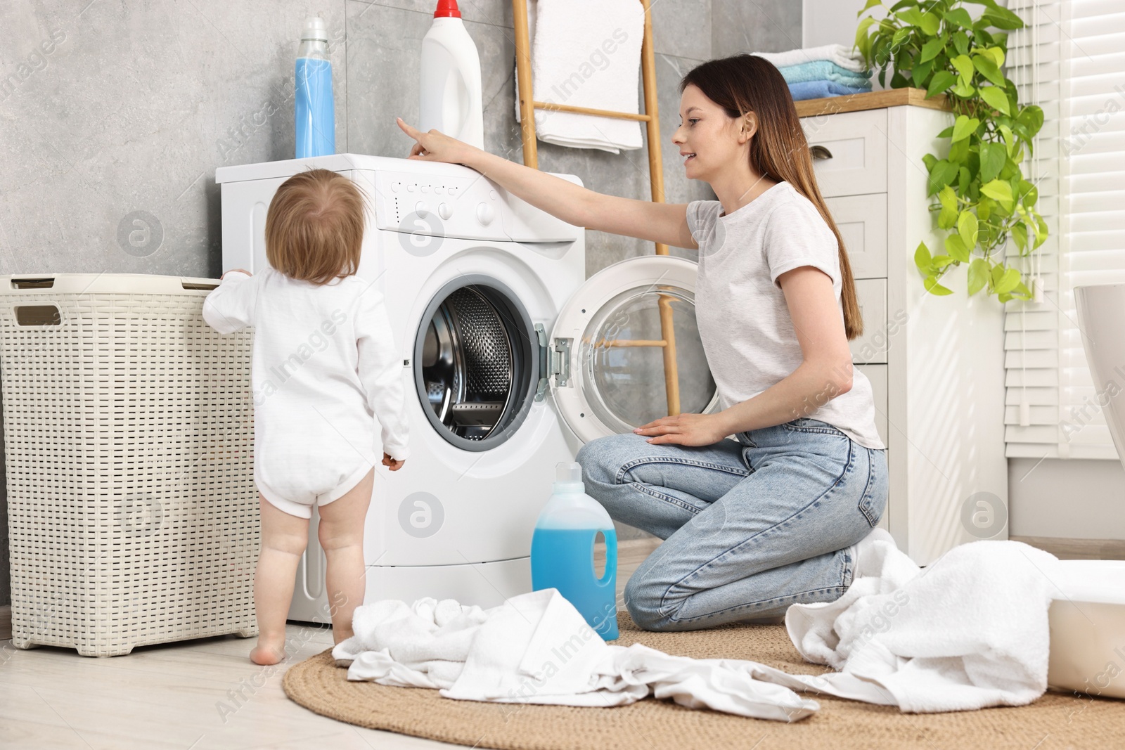 Photo of Mother with her daughter washing baby clothes in bathroom