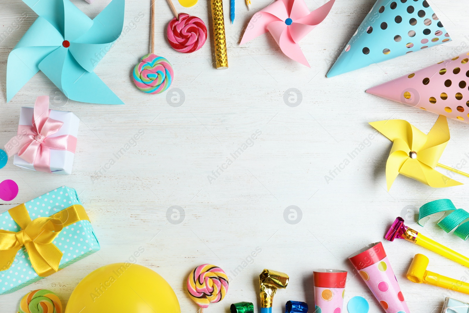 Photo of Frame made of different birthday party items on white wooden table, flat lay. Space for text