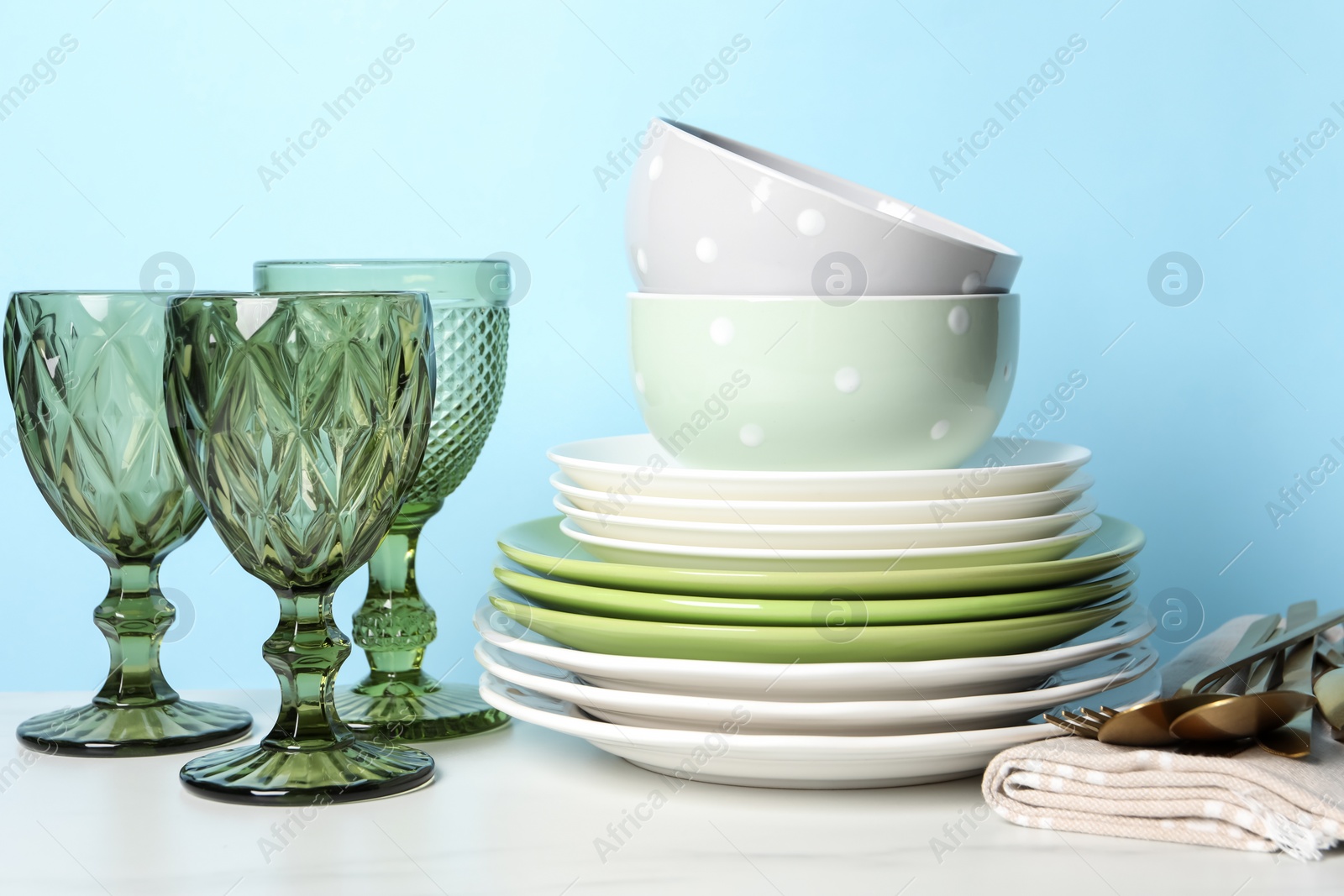 Photo of Beautiful ceramic dishware, glasses and cutlery on white marble table