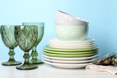 Photo of Beautiful ceramic dishware, glasses and cutlery on white marble table