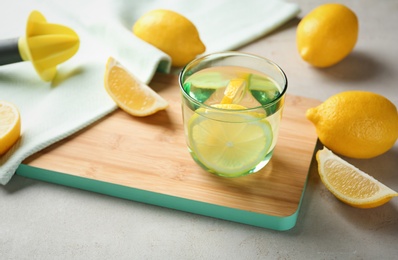 Glass of water with lemon slice on wooden board