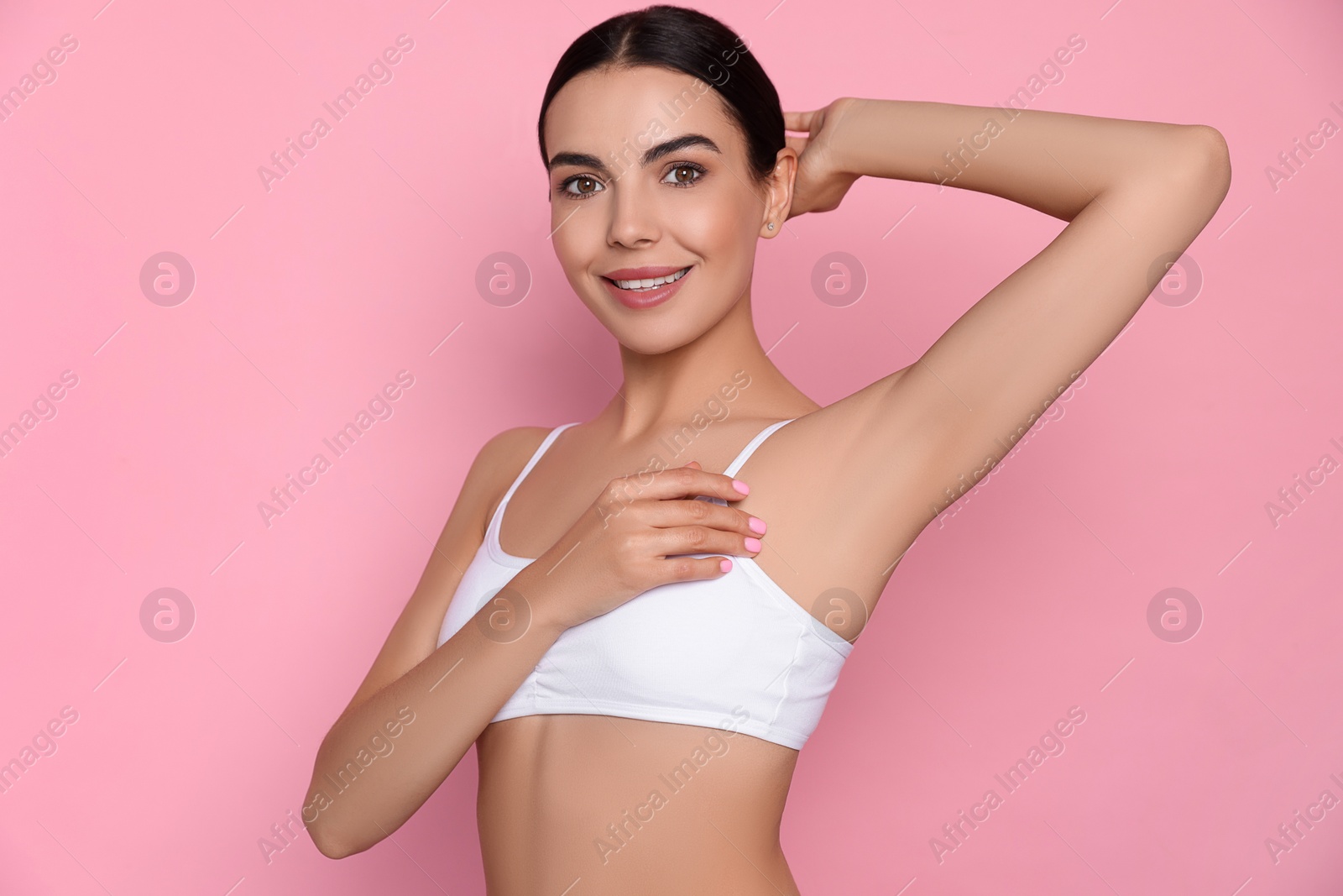 Photo of Young woman showing smooth skin after epilation on pink background