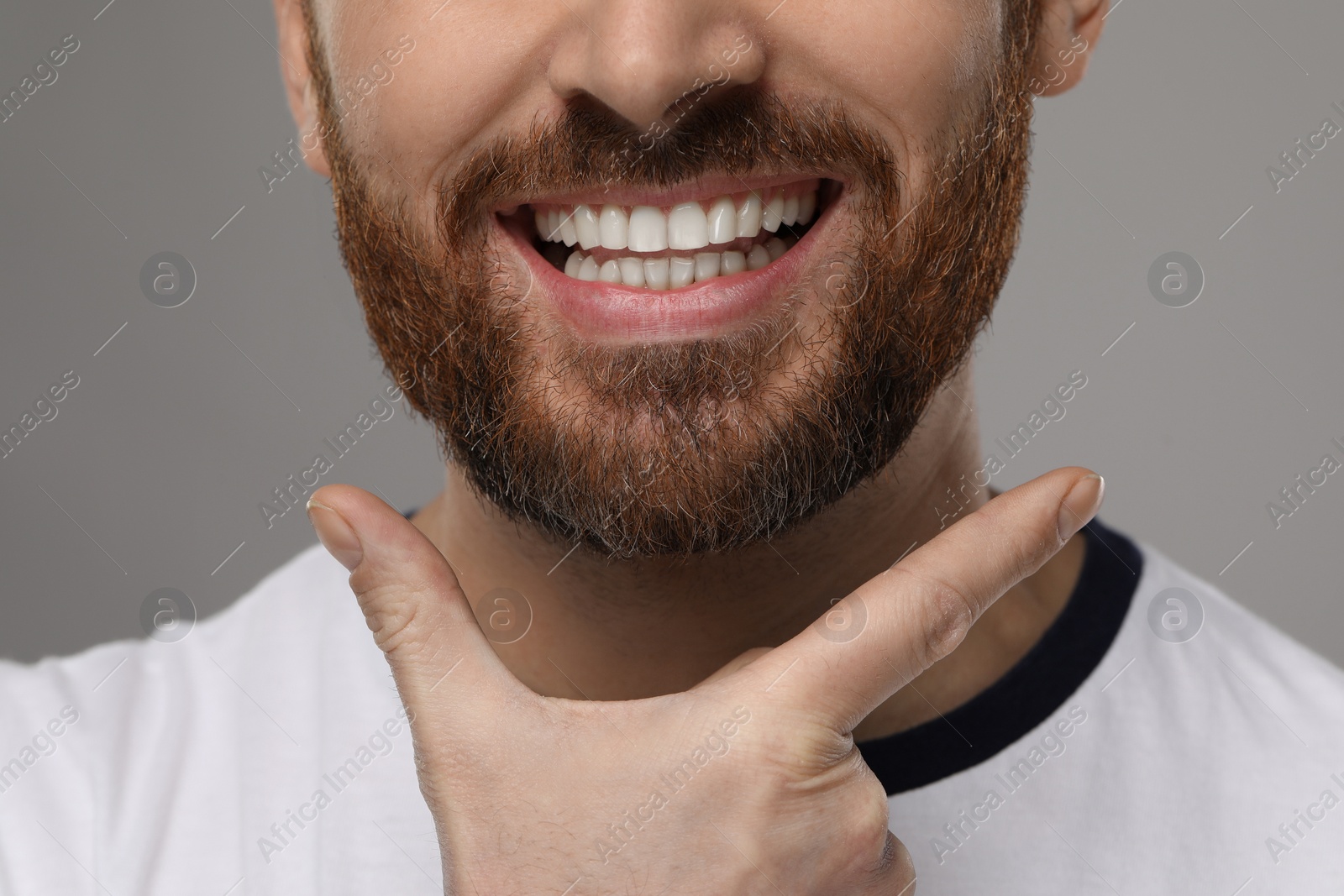 Photo of Smiling man with healthy clean teeth on grey background, closeup