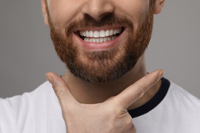 Photo of Smiling man with healthy clean teeth on grey background, closeup