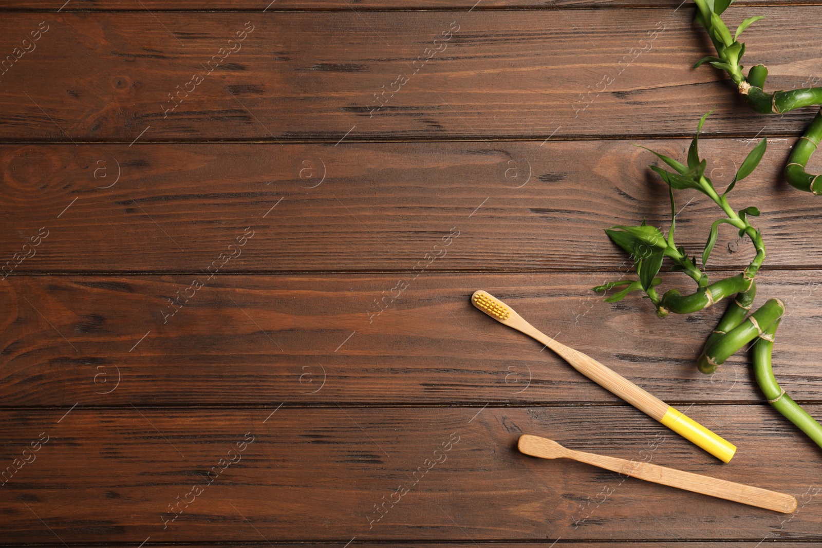 Photo of Flat lay composition with bamboo toothbrushes and space for text on wooden background