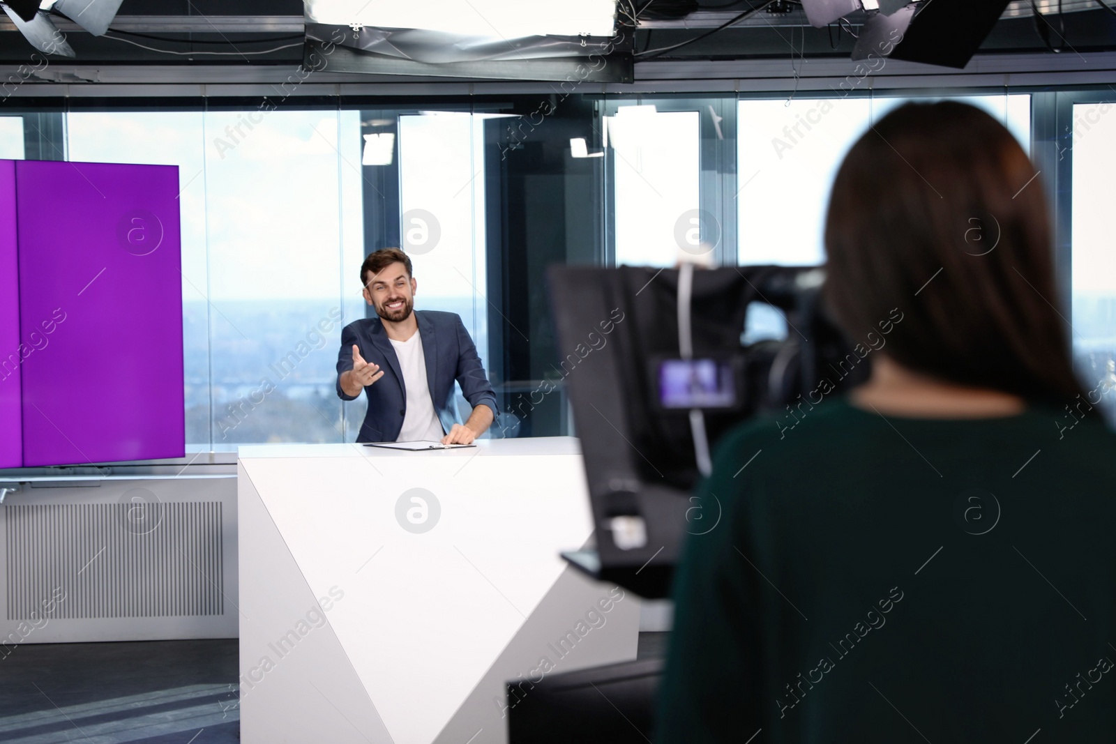 Photo of Presenter and video camera operator working in studio. News broadcasting