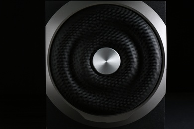 Photo of Modern subwoofer on black background, closeup. Powerful audio speaker
