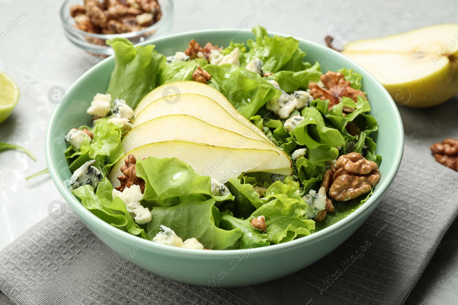 Photo of Tasty salad with pear slices, lettuce and walnuts on table, closeup