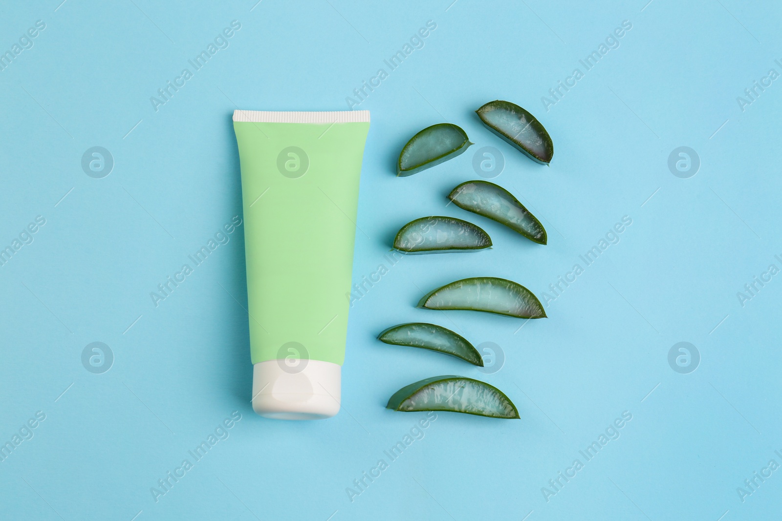 Photo of Tube of toothpaste and fresh cut aloe on light blue background, flat lay