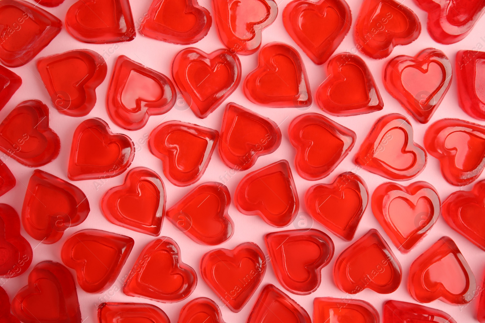 Photo of Sweet heart shaped jelly candies on pink background, flat lay