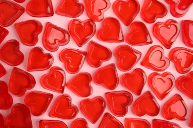 Sweet heart shaped jelly candies on pink background, flat lay