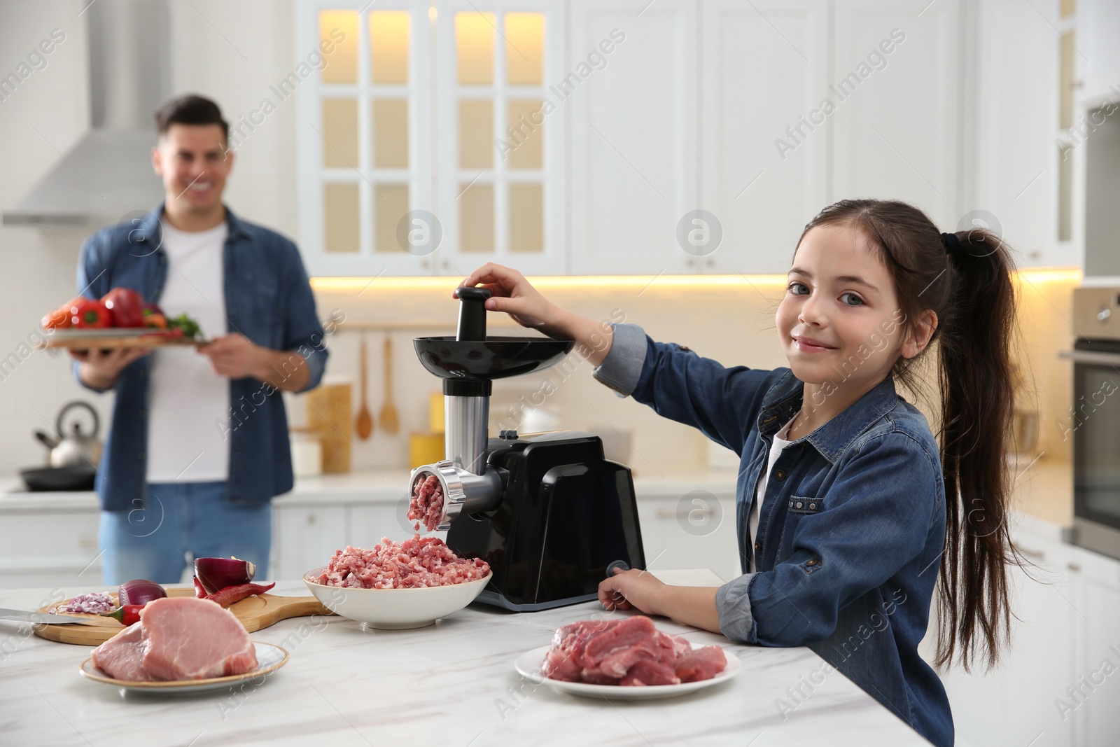 Photo of Little girl using modern meat grinder in kitchen