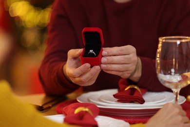 Man with engagement ring making proposal to his girlfriend at home on Christmas, closeup