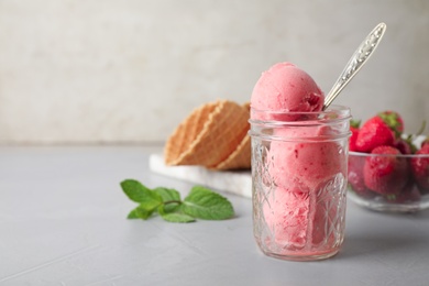Photo of Delicious pink ice cream served in jar on grey table. Space for text