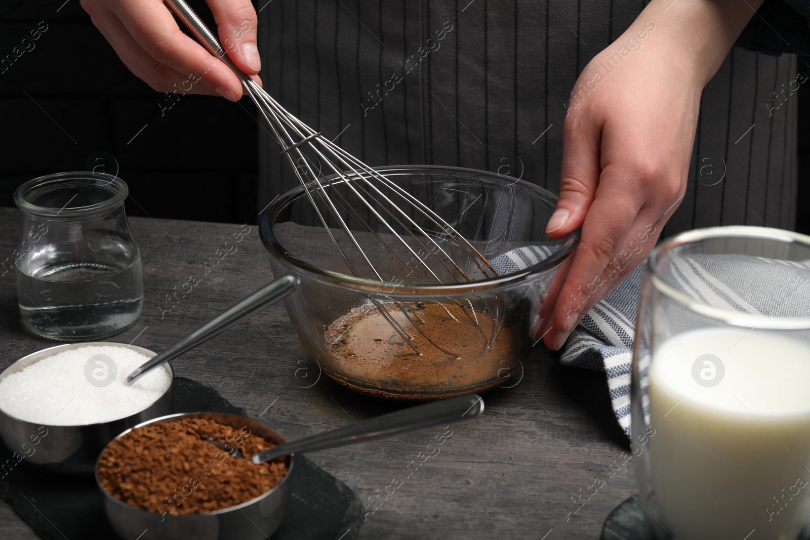 Photo of Woman whipping cream for dalgona coffee at grey table, closeup