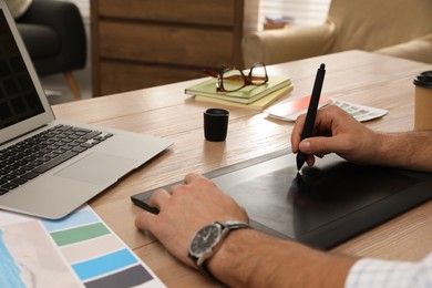 Photo of Professional designer with graphic tablet at wooden table, closeup