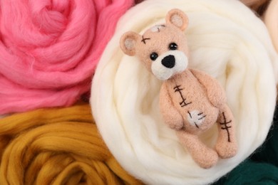 Felted bear on colorful wool, top view