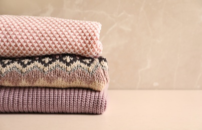 Photo of Stack of warm knitted clothes on table