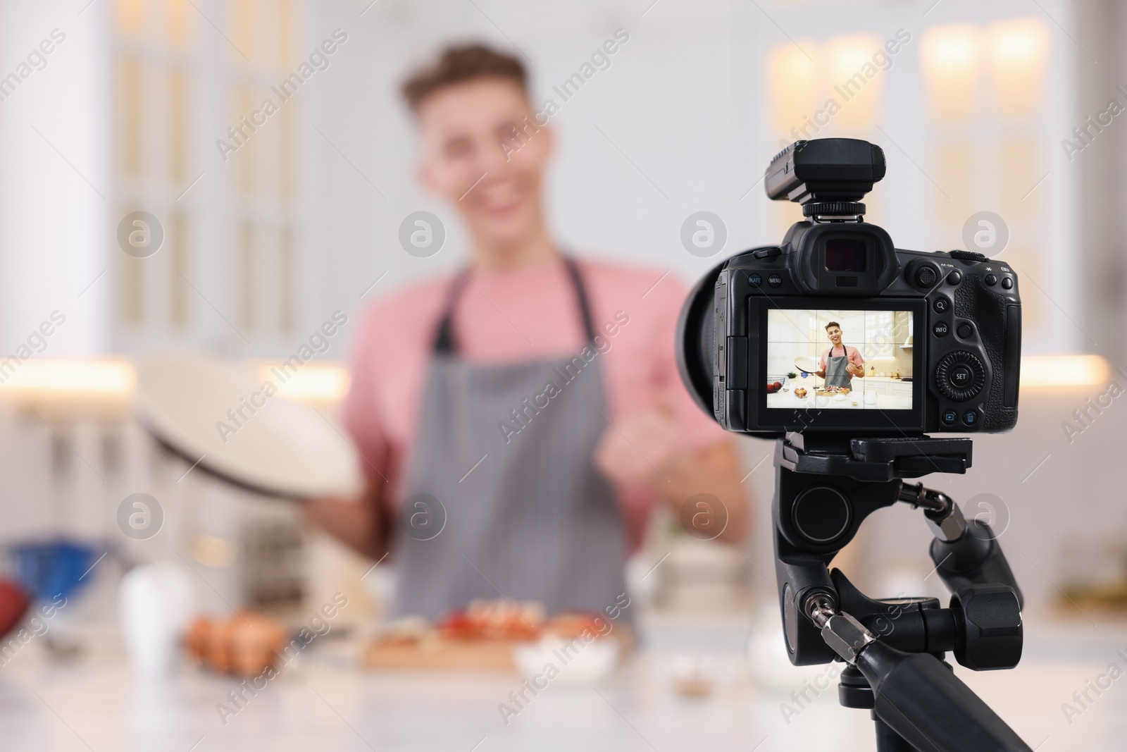 Photo of Food blogger recording video in kitchen, focus on camera