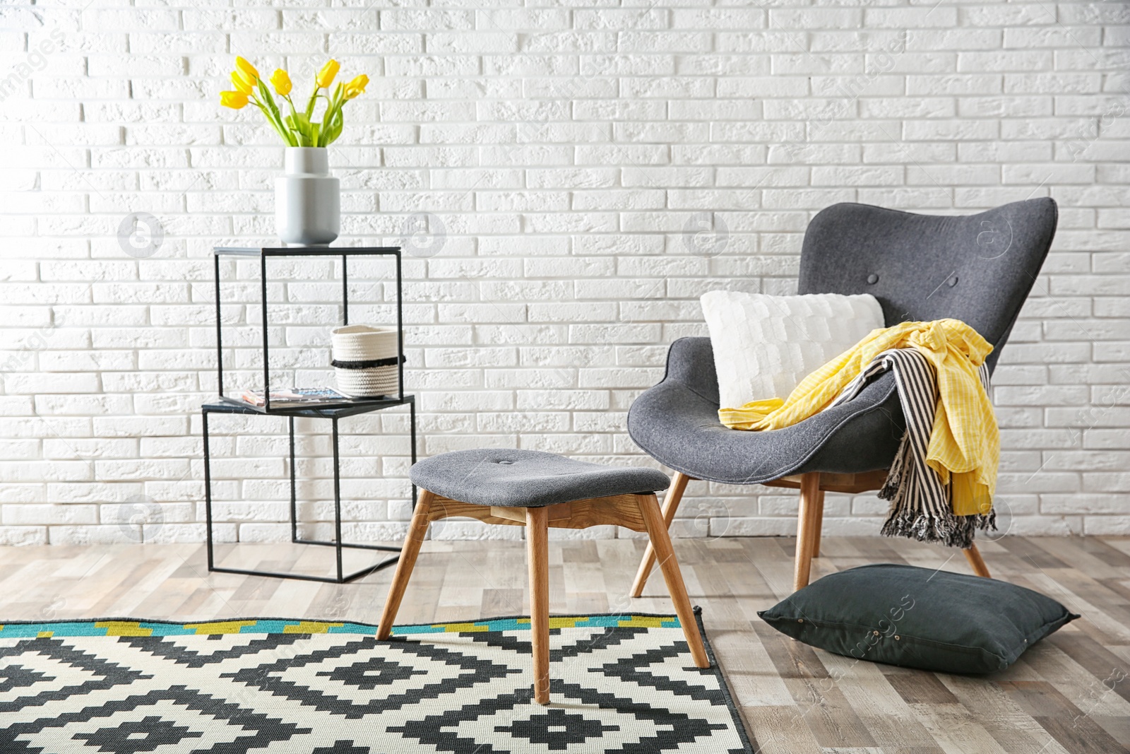 Photo of Modern living room interior with comfortable armchair and stool near brick wall