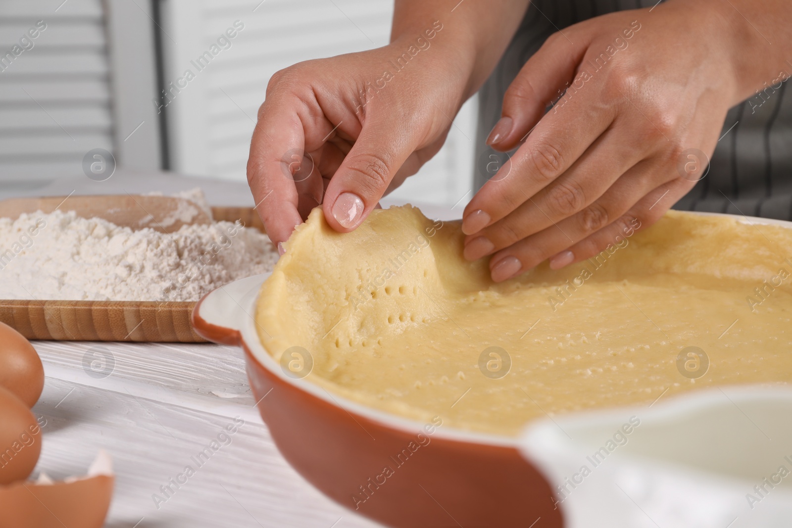 Photo of Woman making quiche at white wooden table, closeup