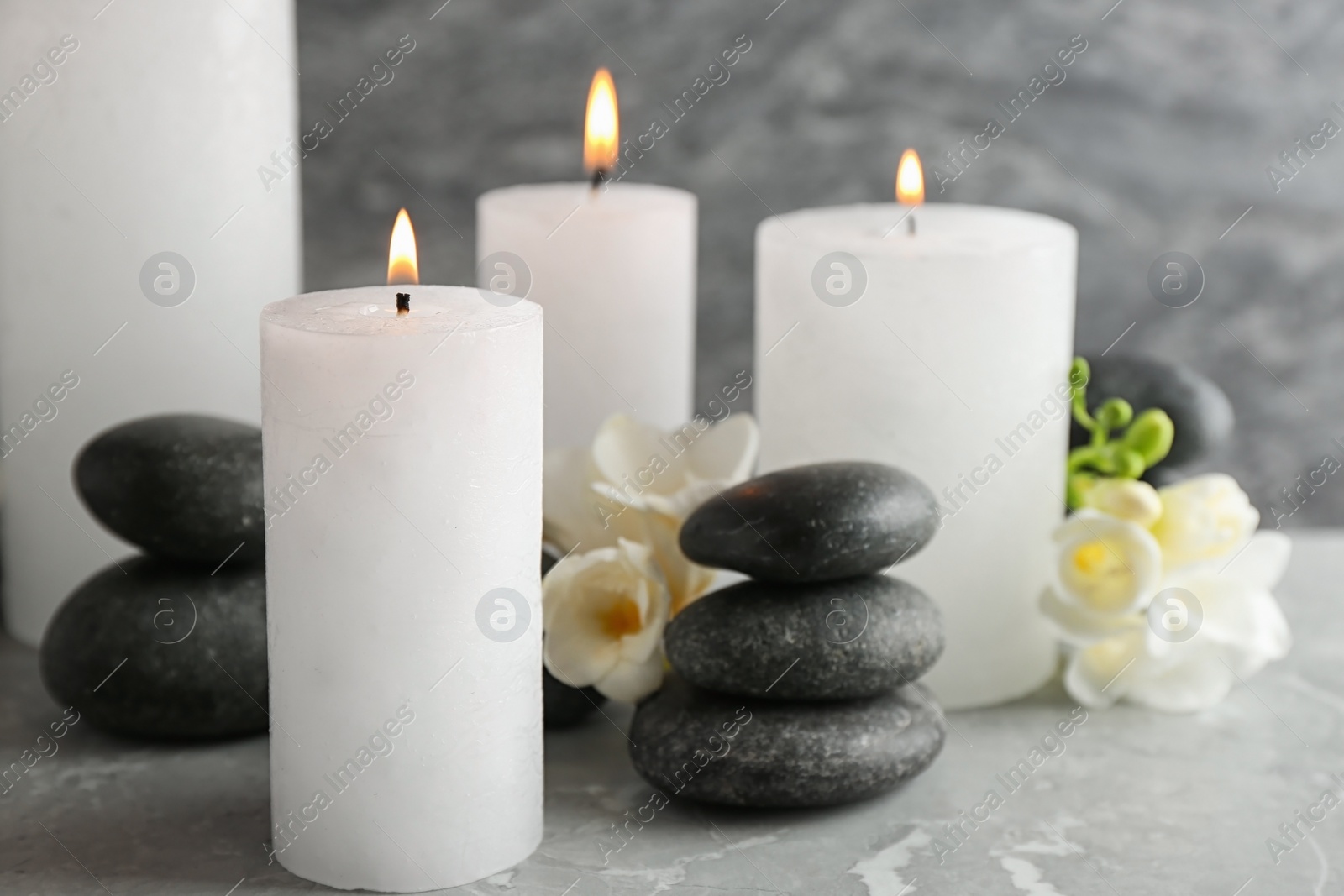 Photo of Burning candles, spa stones and flowers on table. Space for text